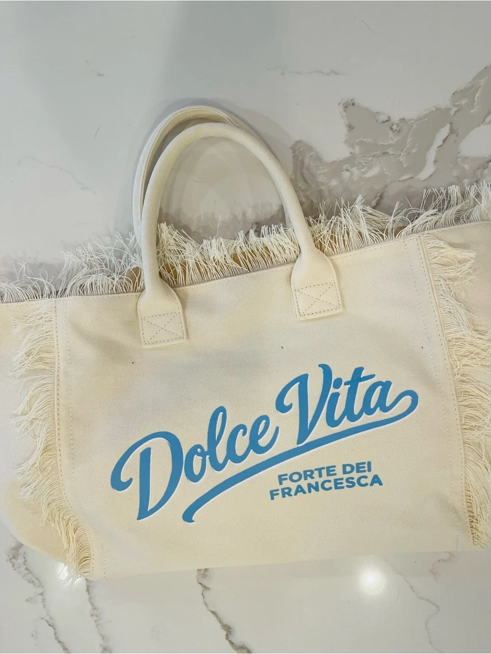Dolce Vita Cream Canvas Fringe Tote with Light Blue Logo
